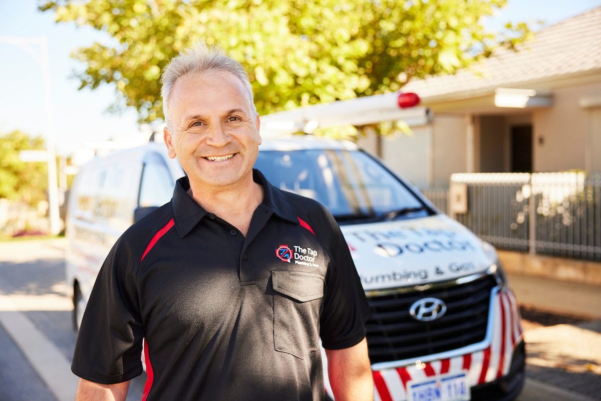 Tap Doctor plumber smiling in front of a Tap Doctor van